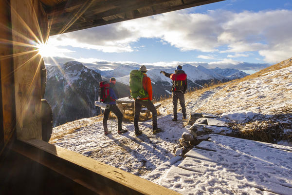 Hikers admiring sunrise from an alpine hut. Livigno, Valtellina, Italy