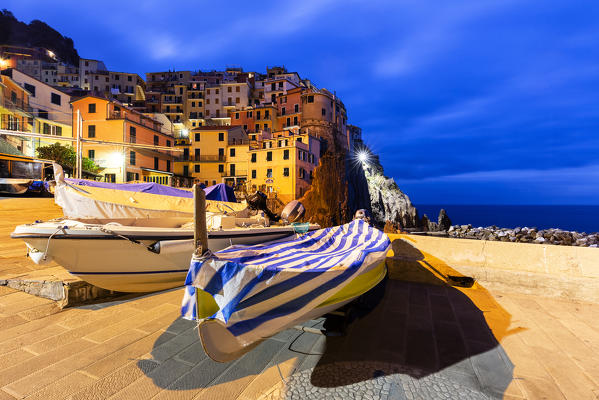 Boats with the village of Manarola at dusk. Cinque Terre, Liguria, Italy, Europe.