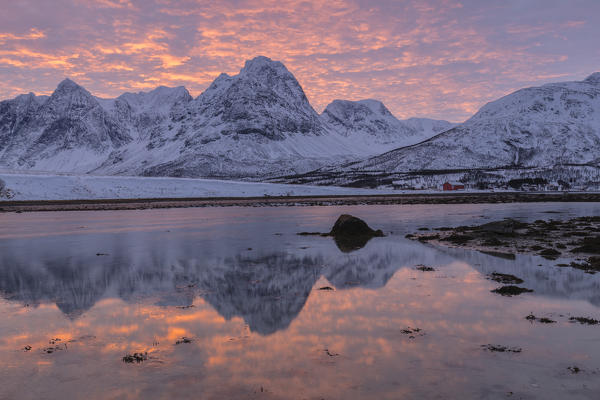 Rakeltinden is reflected in the fjord during sunrise. Storsteinnes, Balsfjorden, Lyngen Alps, Troms, Norway, Lapland, Europe.