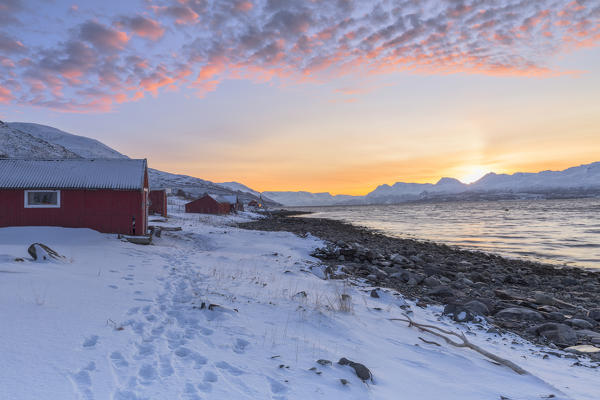 Sunset among the fishermen's houses overlooking the fjord. Nordmannvik, Kafjord, Lyngen Alps, Troms, Norway, Lapland, Europe.