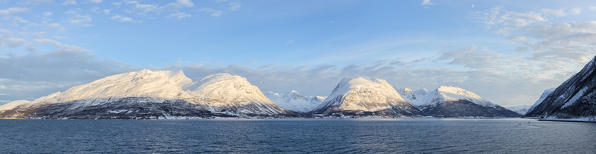 View of the peaks overlooking the fjord while sailing by ferry. Lyngenfjord, Lyngen Alps, Troms, Norway, Lapland, Europe.