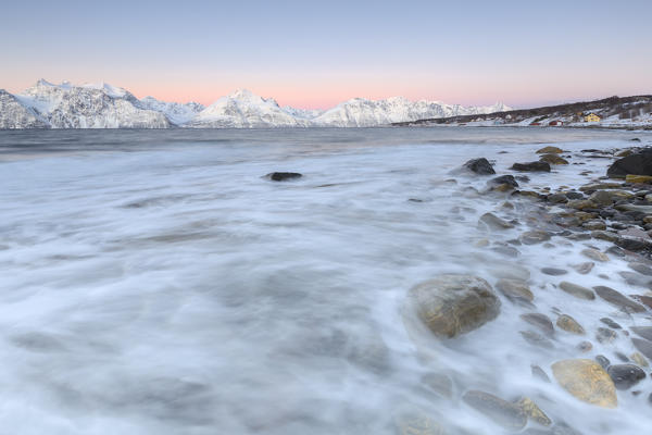 The waves breaking on a beach overlooking the Lyngen Alps during sunrise. Hammarvika, Lyngenfjord, Lyngen Alps, Troms, Norway, Lapland, Europe.