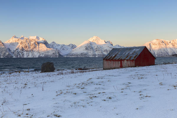 Traditional red house overlooking the fjord. Hammarvika, Lyngenfjord, Lyngen Alps, Troms, Norway, Lapland, Europe.
