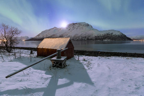 Northern lights over the fjord illuminates by the moon. Ravelseidet, Rotsundet, Lyngenfjord, Lyngen Alps, Troms, Norway, Lapland, Europe.