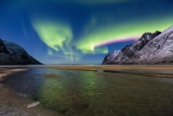 Pink and green northern lights in the night sky over Ersfjord Beach. Ersfjord, Ersfjorden, Senja, Norway, Europe.
