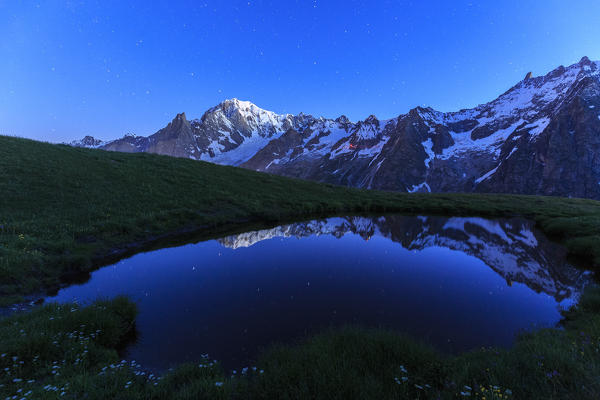 The Mont Blanc is reflected in a puddle during a starry night. Mont de la Saxe, Ferret Valley, Courmayeur, Aosta Valley, Italy, Europe