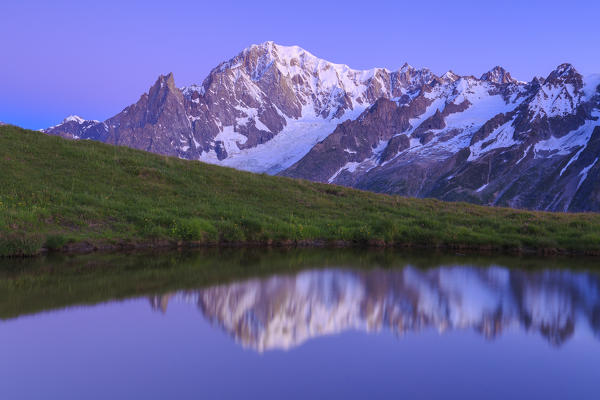 Mont Blanc is reflected in the water at dusk. Mont de la Saxe, Ferret Valley, Courmayeur, Aosta Valley, Italy, Europe