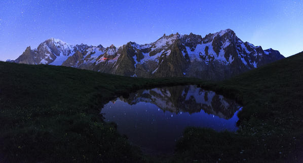 The Mont Blanc mountain range is reflected in a puddle during the night. Mont de la Saxe, Ferret Valley, Courmayeur, Aosta Valley, Italy, Europe