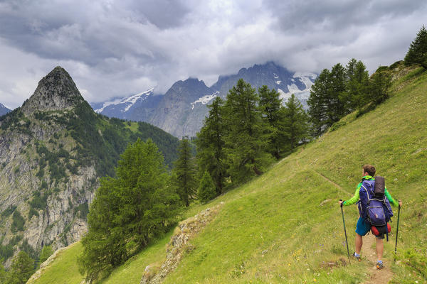 Hiker watches the threatening sky. Bertone Hut, Ferret Valley, Courmayeur, Aosta Valley, Italy, Europe