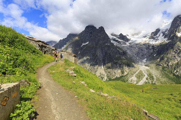 Hikers go on a trail in Val Ferret. Bonatti Hut, Ferret Valley, Courmayeur,  Aosta Valley, Italy, Europe