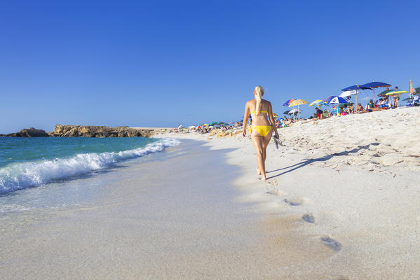 Young girl wit yellow swimsuit walks on the beach of Is Arutas, Cabras, Oristano province, Sardinia, Italy, Europe.