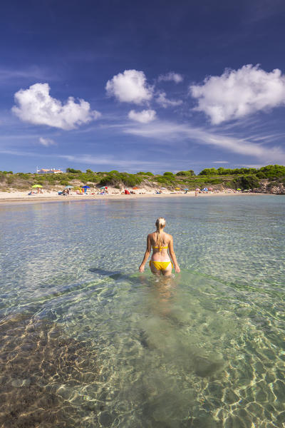 A girl with swimsuit walks in the transparent water. La Bobba Beach, San Pietro Island, Sud Sardegna province, Sardinia, Italy, Europe.