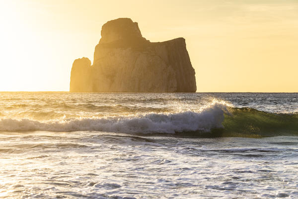 The waves break at sunset with the rock of Pan di Zucchero in the background. Beach of Masua, Iglesias, Sud Sardegna province, Sardinia, Italy, Europe.