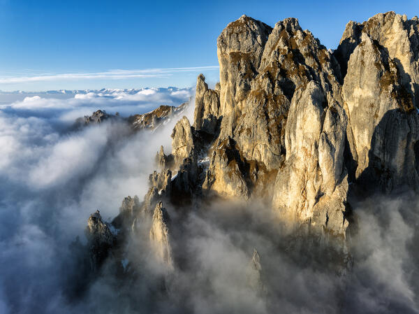 The rock towers of the southern Grigna emerge from the clouds. Grignetta, Grigne group, Lake Como, Italy, Europe