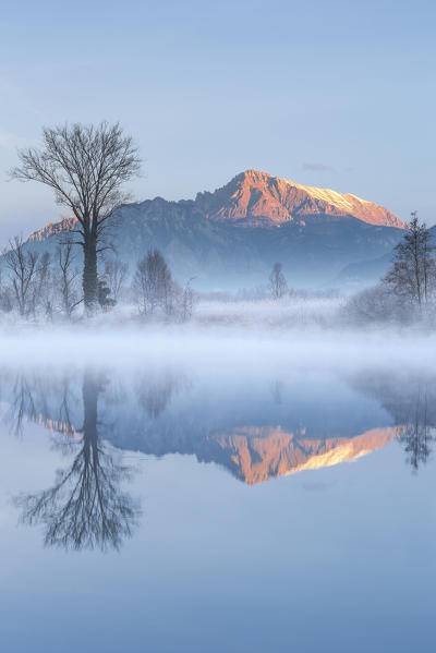 First lights on Grignetta mount (Grigna Meridionale) reflected on Adda river, Airuno, Brianza, Lecco province, Lombardy, Italy, Europe
