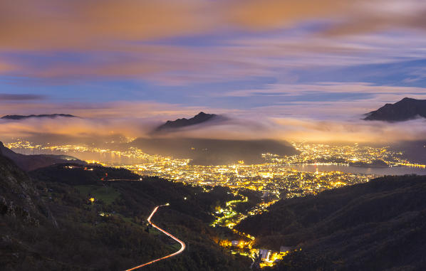 Night lights of lecco city wrapped by clouds, lake Como, Lombardy, Italy, Europe