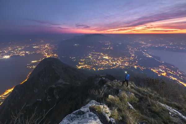 Hiker looks sunset and the lights of Brianza from the top of Barro mount, Lecco province, Lombardy, Italy, Europe (MR)