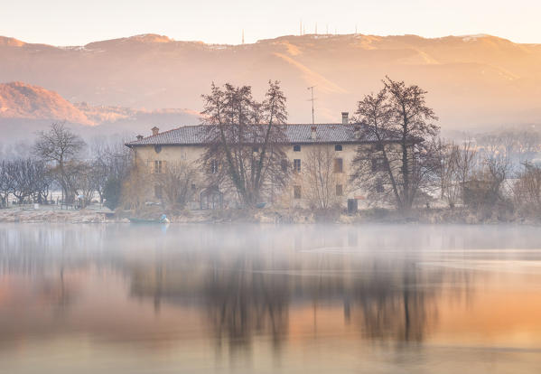 Sunrise on a farmhouse reflected on Adda river, Brivio, Lecco province, Lombardy, Italy, Europe