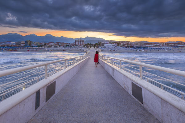 Girl walks at dawn on Lido di Camaiore pier, Lucca province, Versilia, Tuscany, Italy, Europe (MR)