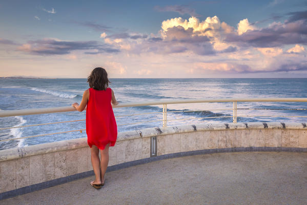 Girl looks the sunrise on Lido di Camaiore pier, Lucca province, Versilia, Tuscany, Italy, Europe (MR)