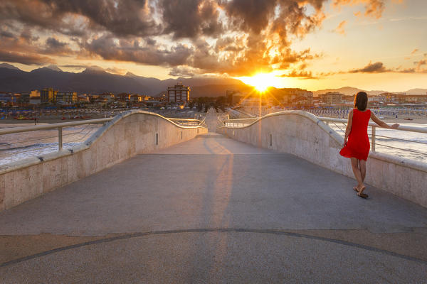 Girl looks the sunrise on Lido di Camaiore pier, Lucca province, Versilia, Tuscany, Italy, Europe (MR)