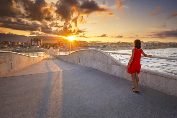 Girl looks the sunrise on Lido di Camaiore pier, Lucca province, Versilia, Tuscany, Italy, Europe (MR)