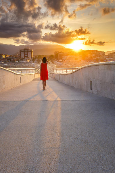 Girl looks the sunrise on Lido di Camaiore pier, Lucca province, Versilia, Tuscany, Italy, Europe (MR)