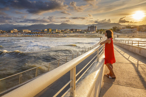 Girl looks the sea at sunrise on Lido di Camaiore pier, Lucca province, Versilia, Tuscany, Italy, Europe (MR)