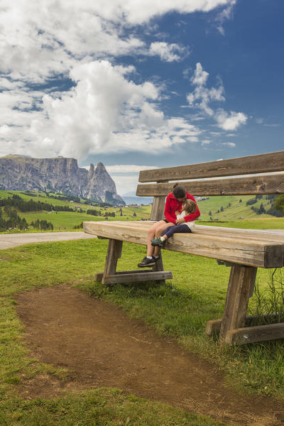 Mom and daughter hug on the giants bench, Alpe di Siusi/Seiser Alm, Sciliar group Dolomites, South Tyrol, Bolzano province, Trentino Alto Adige, Italy, Europe (MR)