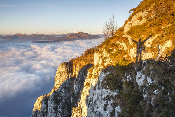 The shadow of hiker triumph from the top of Coltignone mount at sunrise, Piani dei Resinelli, Lecco province, Lombardy, Italy, Europe (MR)