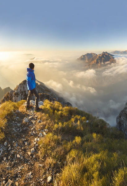 Hiker look the Lecco mountains (Corni di Canzo, Rai, Moregallo) wrapped of clouds from the top of Coltignone mount, Piani dei Resinelli, Lecco province, Lombardy, Italy, Europe (MR)