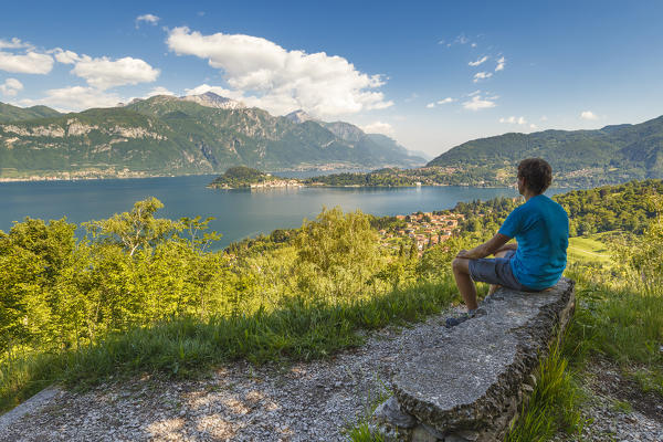 Hiker relaxes looking Bellagio and lake Como from the path to San Martino church, Griante, Como province, Lombardy, Italy, Europe (MR)