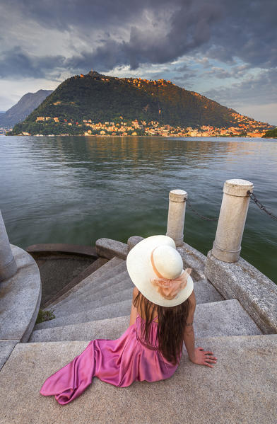A tourist take relax looking lake Como at sunset on the stairs near Olmo villa, Como city, Lombardy, Italy, Europe (MR)