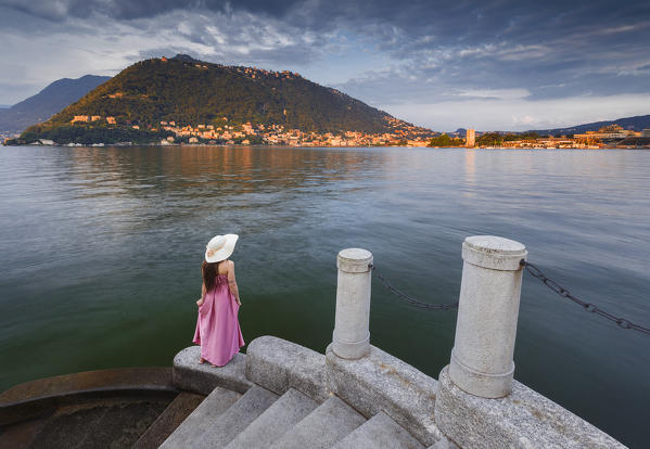 A tourist looking lake Como at sunset on the stairs near Olmo villa, Como city, Lombardy, Italy, Europe (MR)