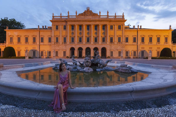Girl sitting on a fountain of Olmo villa at the evening, Como city, Lombardy, Italy, Europe (MR)