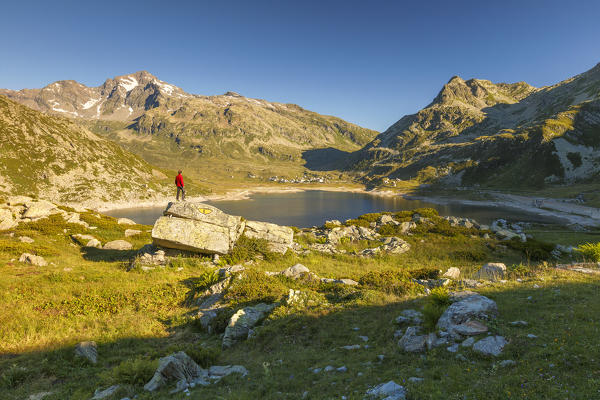 Hiker looks first lights on the rock called Snake of Montespluga, Madesimo, Sondrio province, Spluga valley, Lombardy, Italy, Europe (MR)