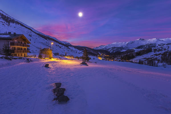 Snowy dawn on Madesimo village with moon, Sondrio province, Spluga valley, Lombardy, Italy, Europe