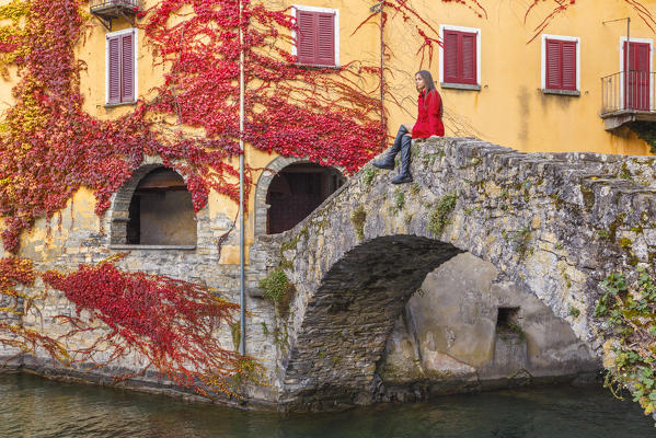 A tourist sitting on Ponte della Civera looks lake Como from Nesso village in Autumn time, Como province, Lombardy, Italy, Europe (MR)
