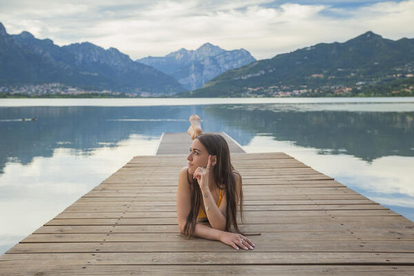 Girl relaxes on the pier of Oggiono lake, Annone lake, Oggiono, Brianza, Lecco province, Lombardy, Italy, Europe (MR)