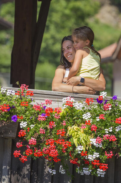 Mom and daughter embrace and look panorama from the wooden bridge (Ponte di Legno di Pellizzano) in a summer time, Pellizzano, Sole valley (val di Sole), Trento province, Trentino-Alto Adige, Italy, Europe (MR)