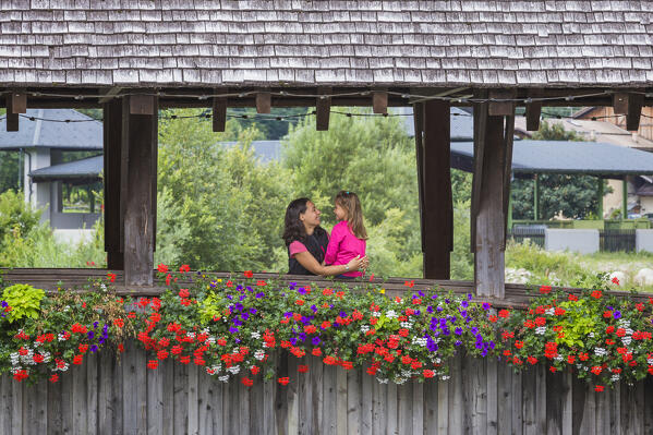 Mom and daughter embrace on the wooden bridge (Ponte di Legno di Pellizzano) in a summer time, Pellizzano, Sole valley (val di Sole), Trento province, Trentino-Alto Adige, Italy, Europe (MR)