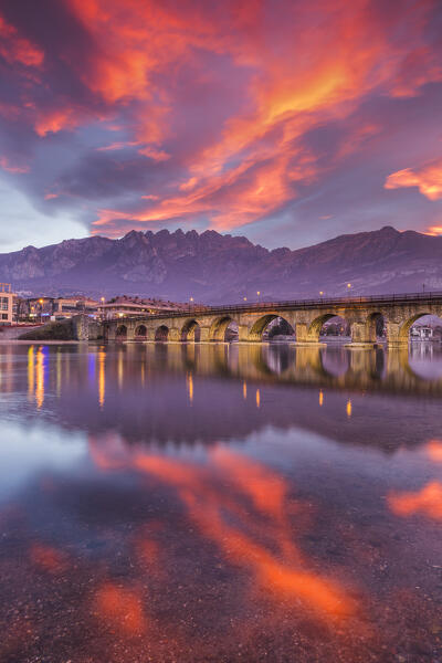Sunrise on Lecco mountains (Resegone) reflected into the Adda River, Azzone Visconti bridge, Lecco city, lake Como, Lombardy, Italy, Europe