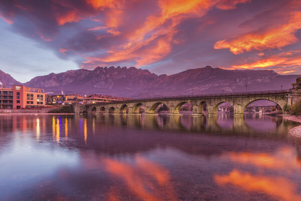 Sunrise on Lecco mountains (Resegone) reflected into the Adda River, Azzone Visconti bridge, Lecco city, lake Como, Lombardy, Italy, Europe