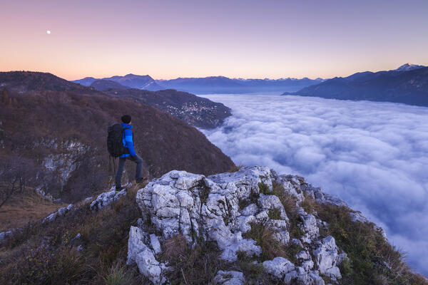 Hiker over the top looks lake Como (ramo di Lecco) covered by the fog at sunrise, Como and Lecco province, Lombardy, Italy, Europe (MR)