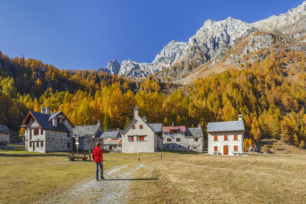 Hiker reaches the Pedemonte village, Alpe Devero, Baceno, Alpe Veglia and Alpe Devero natural park, province of Verbano-Cusio-Ossola, Piedmont, italy, Europe (MR)