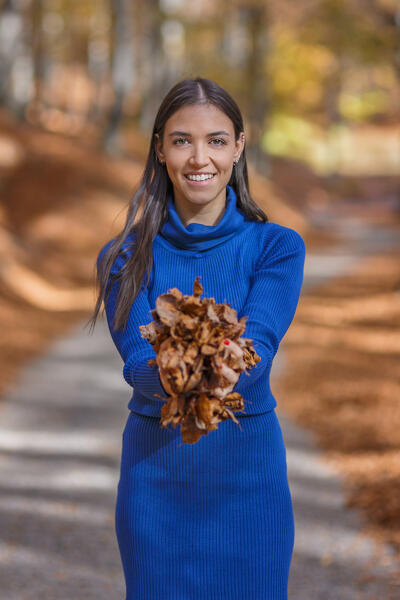 A portrait of a young woman in a blue dress while holding leaves of trees in autumn time, Ponna Superiore, Intelvi valley (val d'Intelvi), Como province, Lombardy, Italy, Europe (MR)
