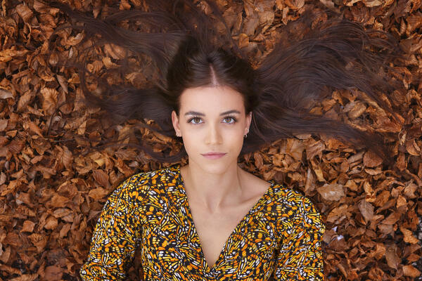 A portrait of a young woman on a leaves carpet in an autumn forest, Ponna Superiore, Intelvi valley (val d'Intelvi), Como province, Lombardy, Italy, Europe (MR)
