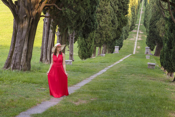 A young woman in red dress along the cypress avenue (Viale dei Cipressi), Brianza, Inverigo, Como province, Lombardy, Italy, Europe (MR)