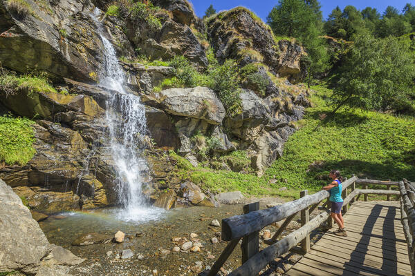 Hiker relaxes and looks Covel waterfall, Peio valley, Stelvio National Park, Trento province, Trentino Alto Adige, Italy, Europe (MR)