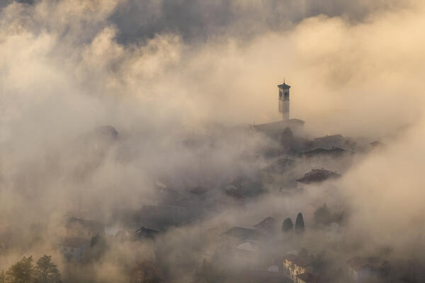 St. Stephen church (chiesa di piazza S. Stefano) wrapped by the morning fog, Cernobbio town, lake Como, Como province, Lombardy, Italy, Europe